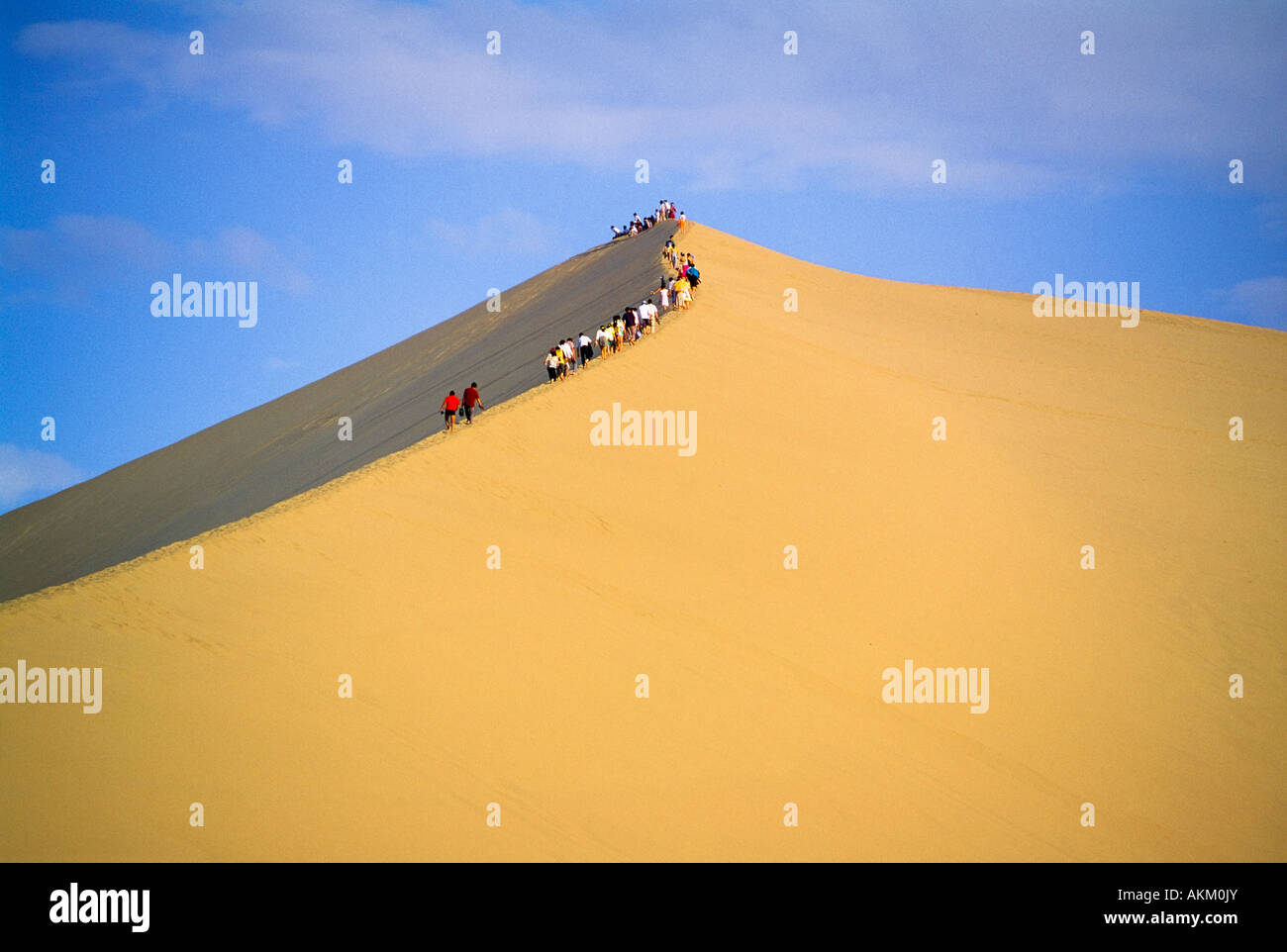 People climbing sand dune Stock Photo