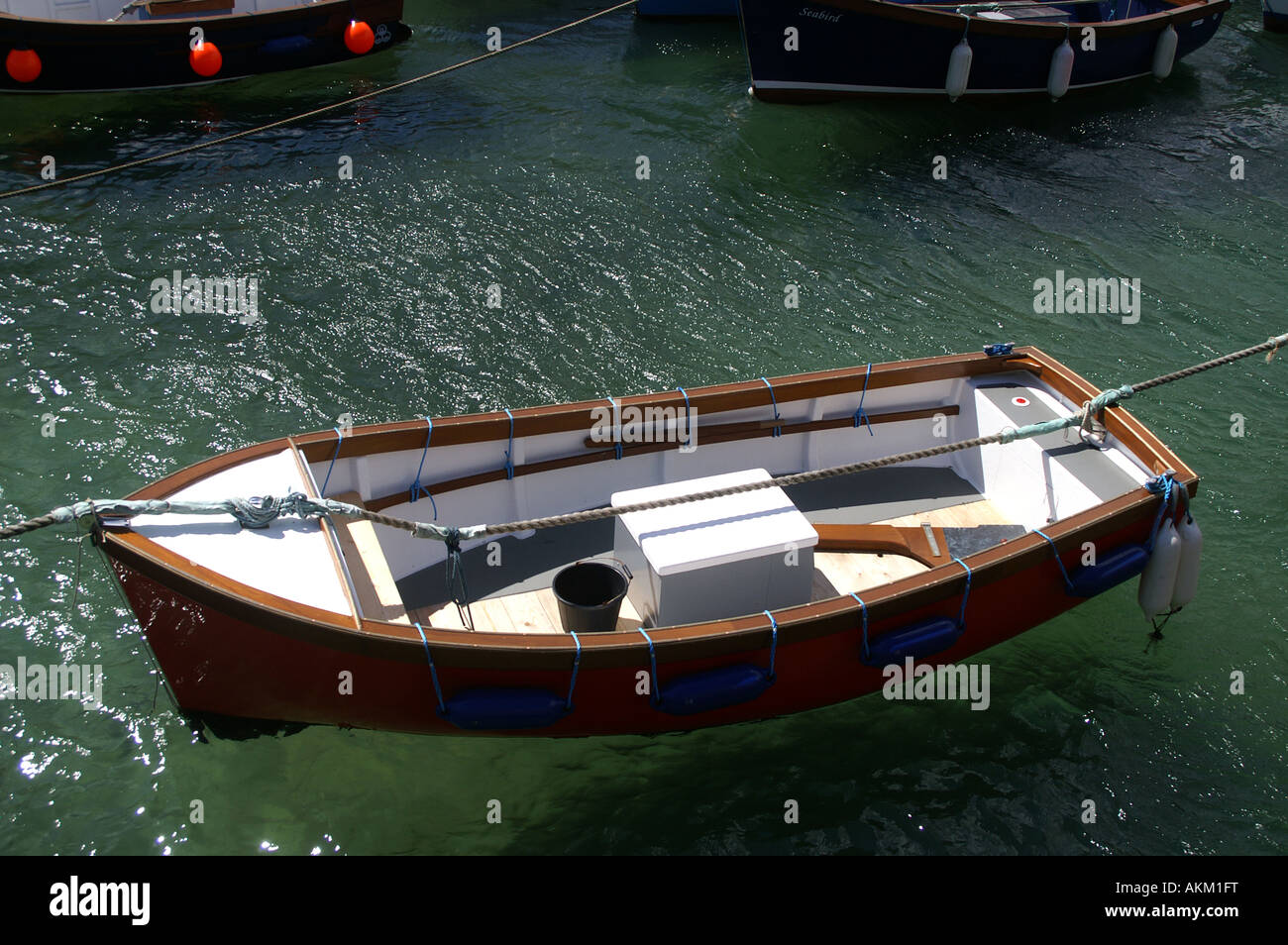 Rowing Boat in a clear with blue bumpers Sea Coverack Harbour Stock Photo
