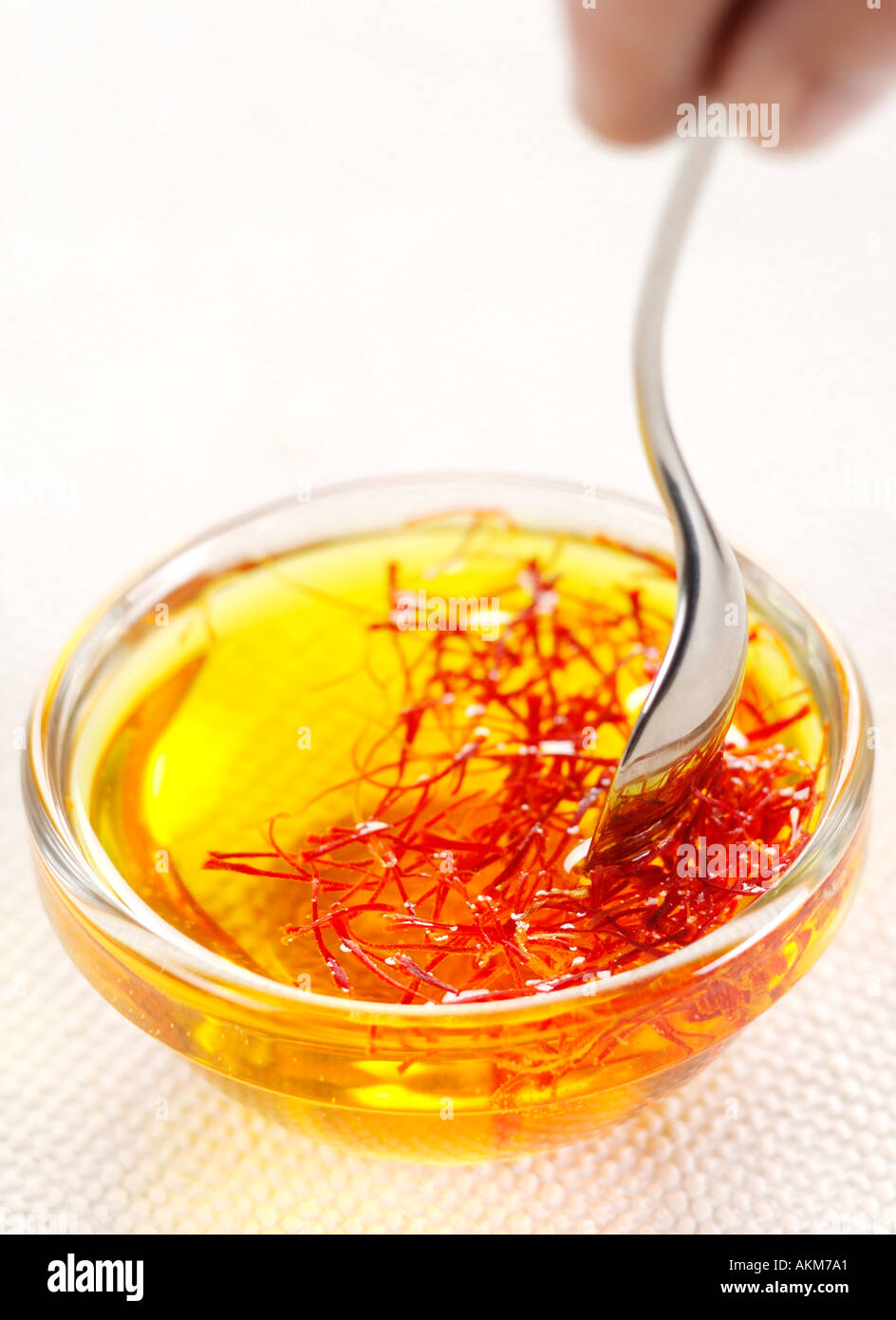 SAFFRON BEING MIXED WITH WATER WITH A SPOON IN A SMALL GLASS BOWL Stock