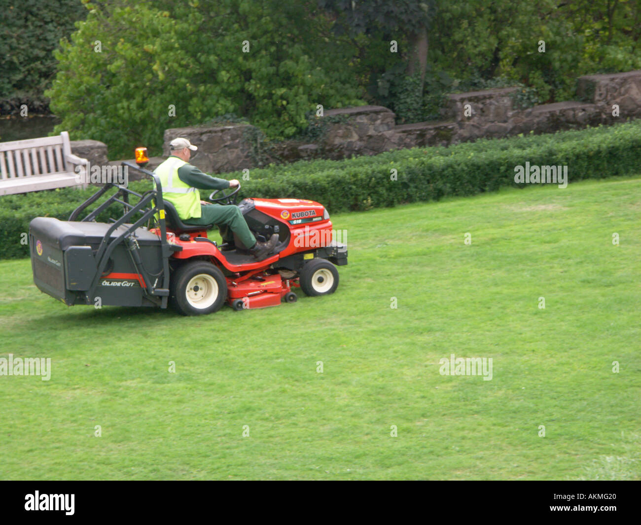 Grass cutting with ride on mower. A council workman cuts the lawn in