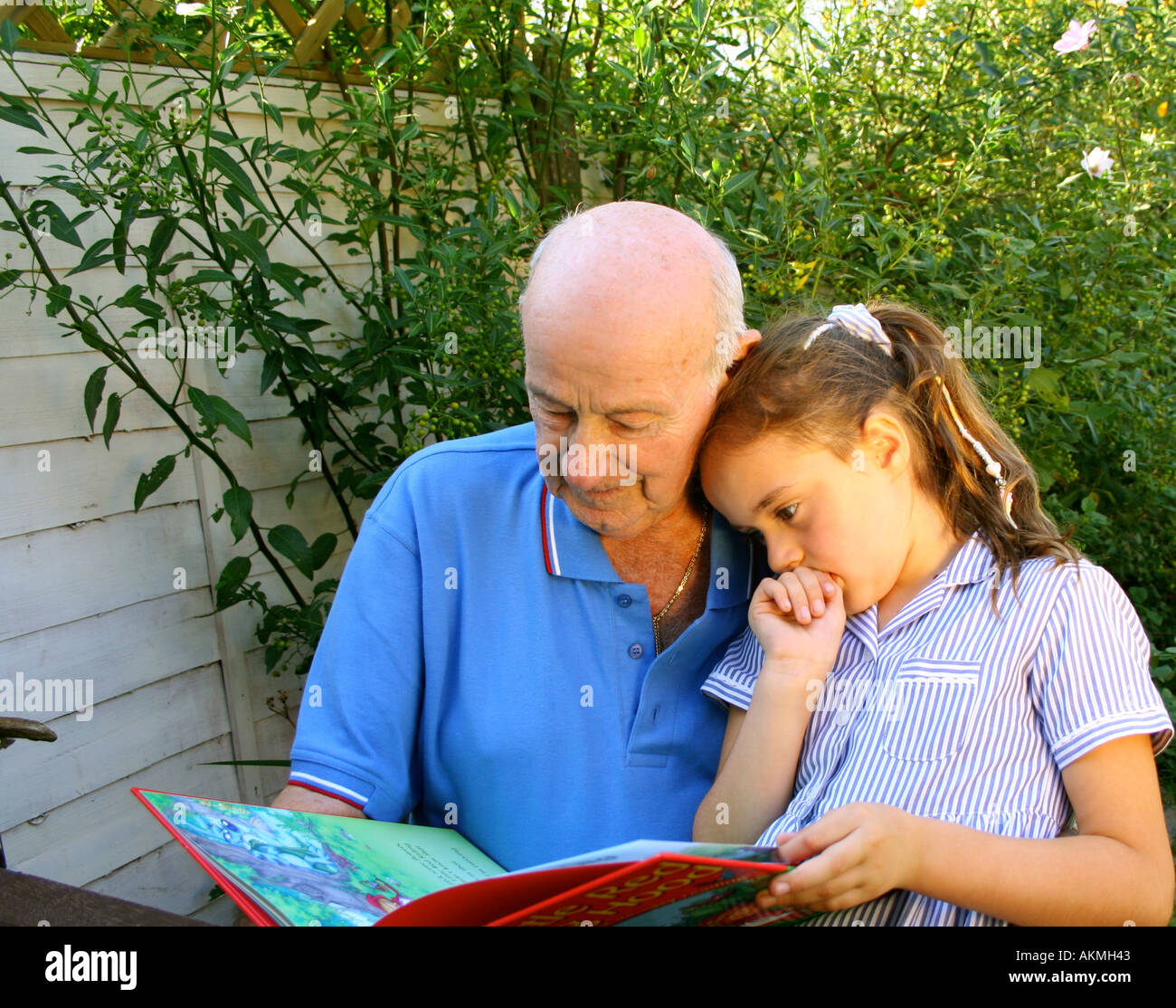 Child Reading with her Grandad Stock Photo