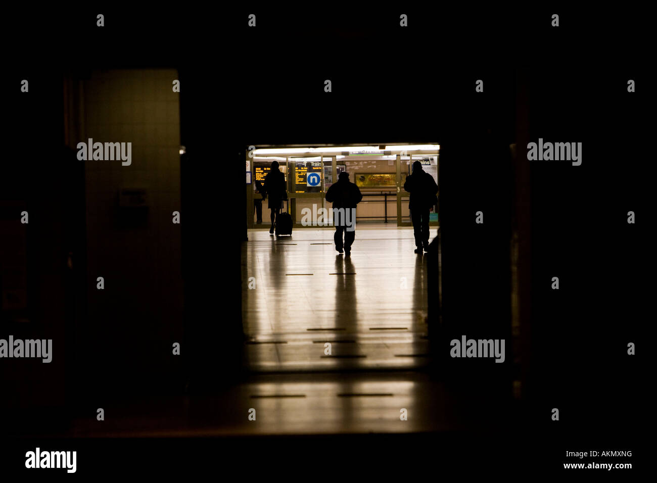 Lonely woman walking into a railway station entrance in the dark followed by 2 men. Birmingham. United Kingdom. Stock Photo