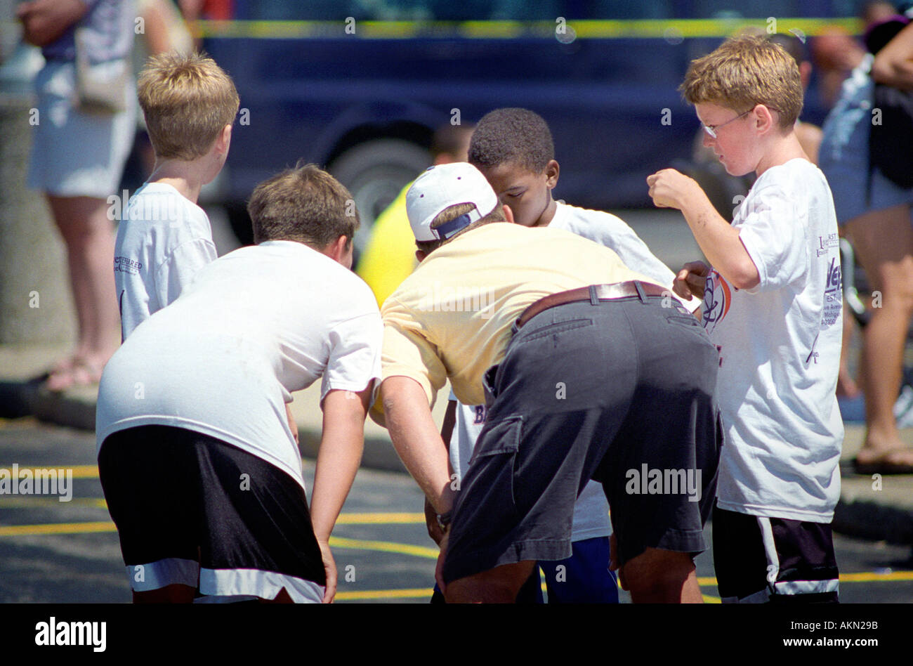 Coach huddles with basketball team members to discuss strategy and offer encouragement Stock Photo