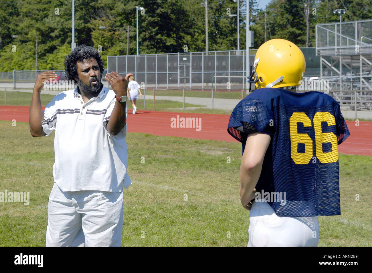 High School Football action Port Huron Michigan Deaf JV football player reads sign language given by black aid during practice Stock Photo