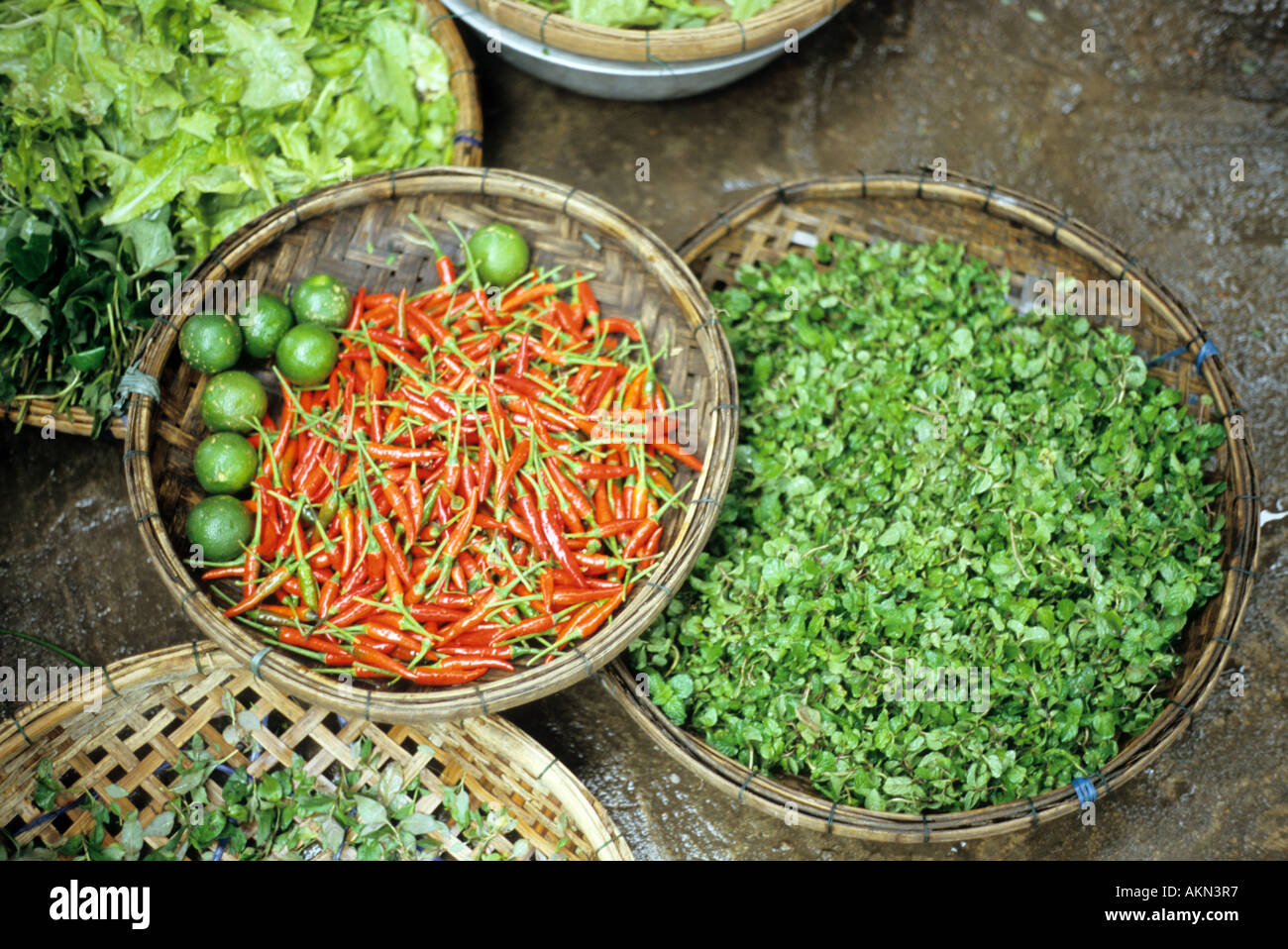 Baskets of fresh herbs, chillies and limes for sale on the road in the Bach Dang St market, Hoi An, Viet Nam Stock Photo