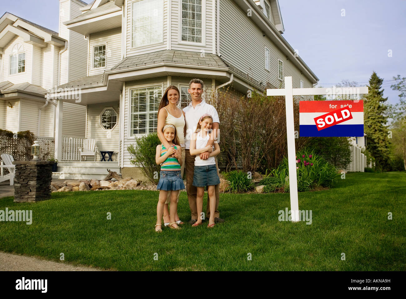 A family standing in front of a house with a sold sign Stock Photo - Alamy