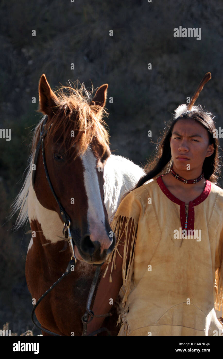 A Native American Indian boy wearing a feather standing next to a horse Stock Photo