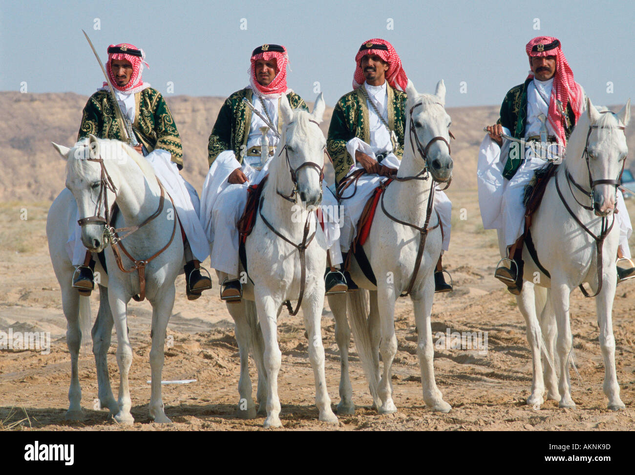 Bedouin men riding horses in the desert in Saudi Arabia Stock Photo