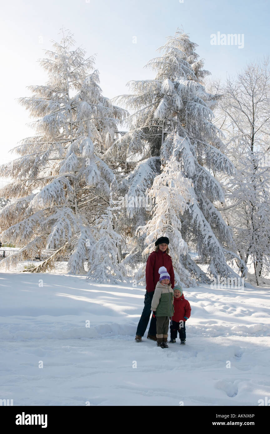 Happy family mother with small boy and girl in winter snow covered city ...