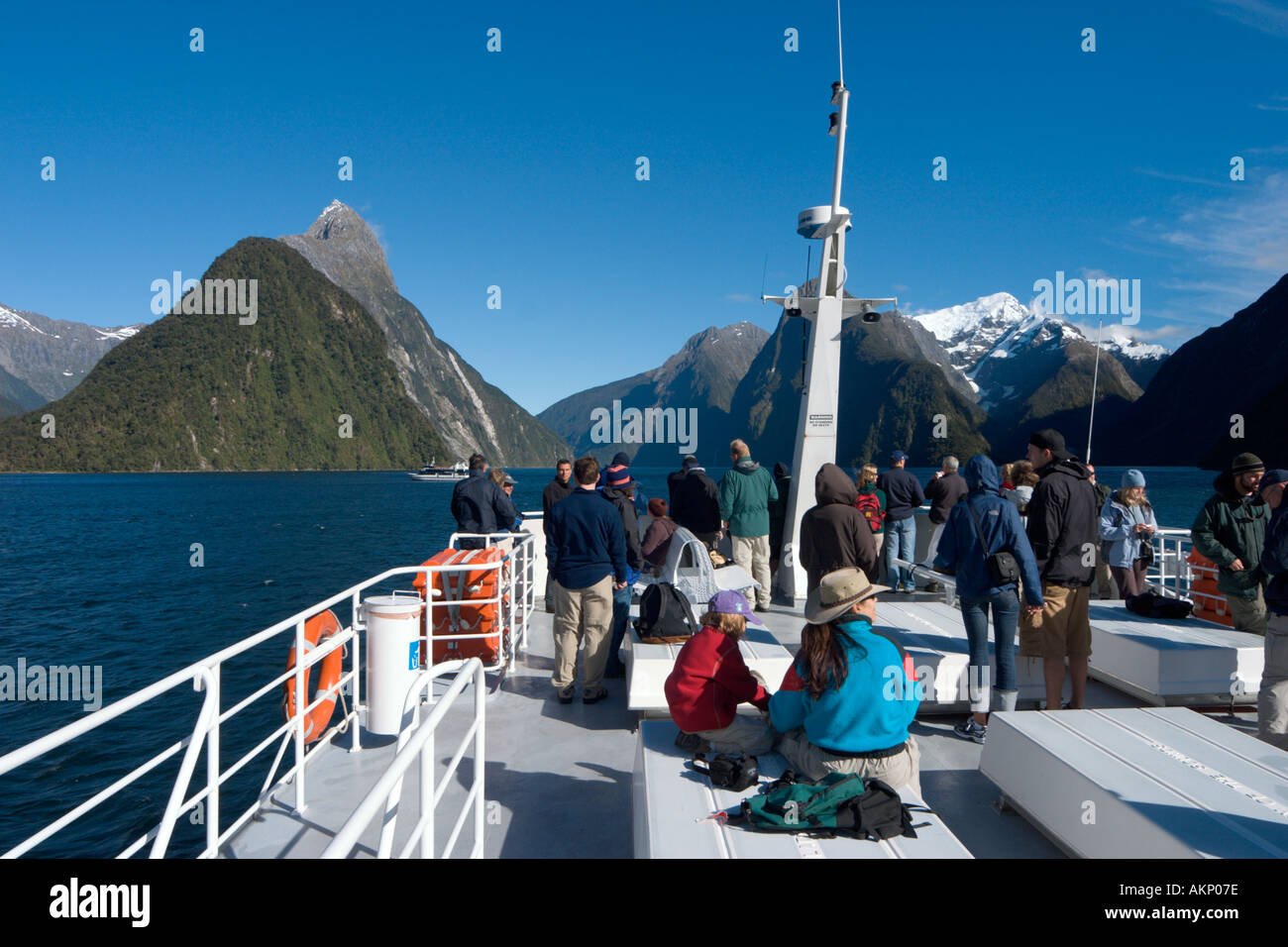 Tourists on the deck of a cruise boat with Mitre Peak behind, Milford Sound, Fiordland National Park, South Island, New Zealand Stock Photo