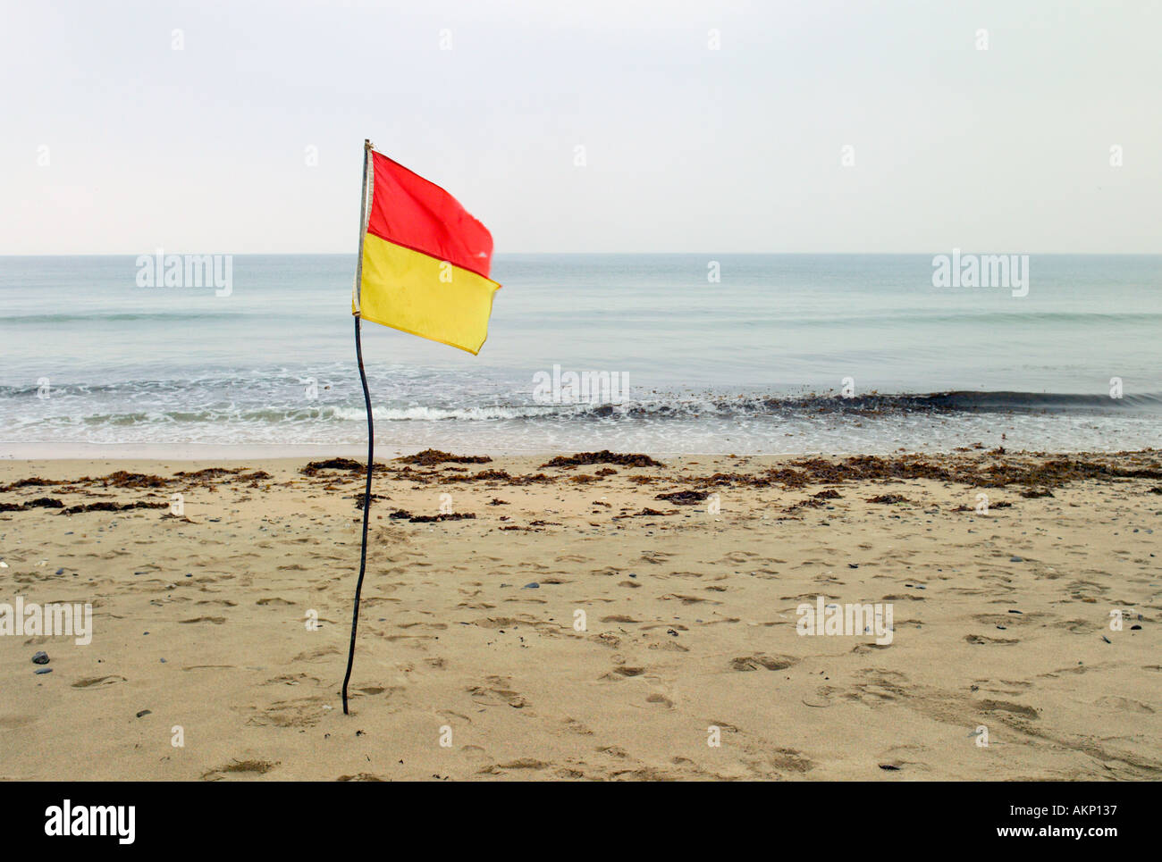 Safety flag on beach in sand Praa Sands Cornwall UK overcast day flat