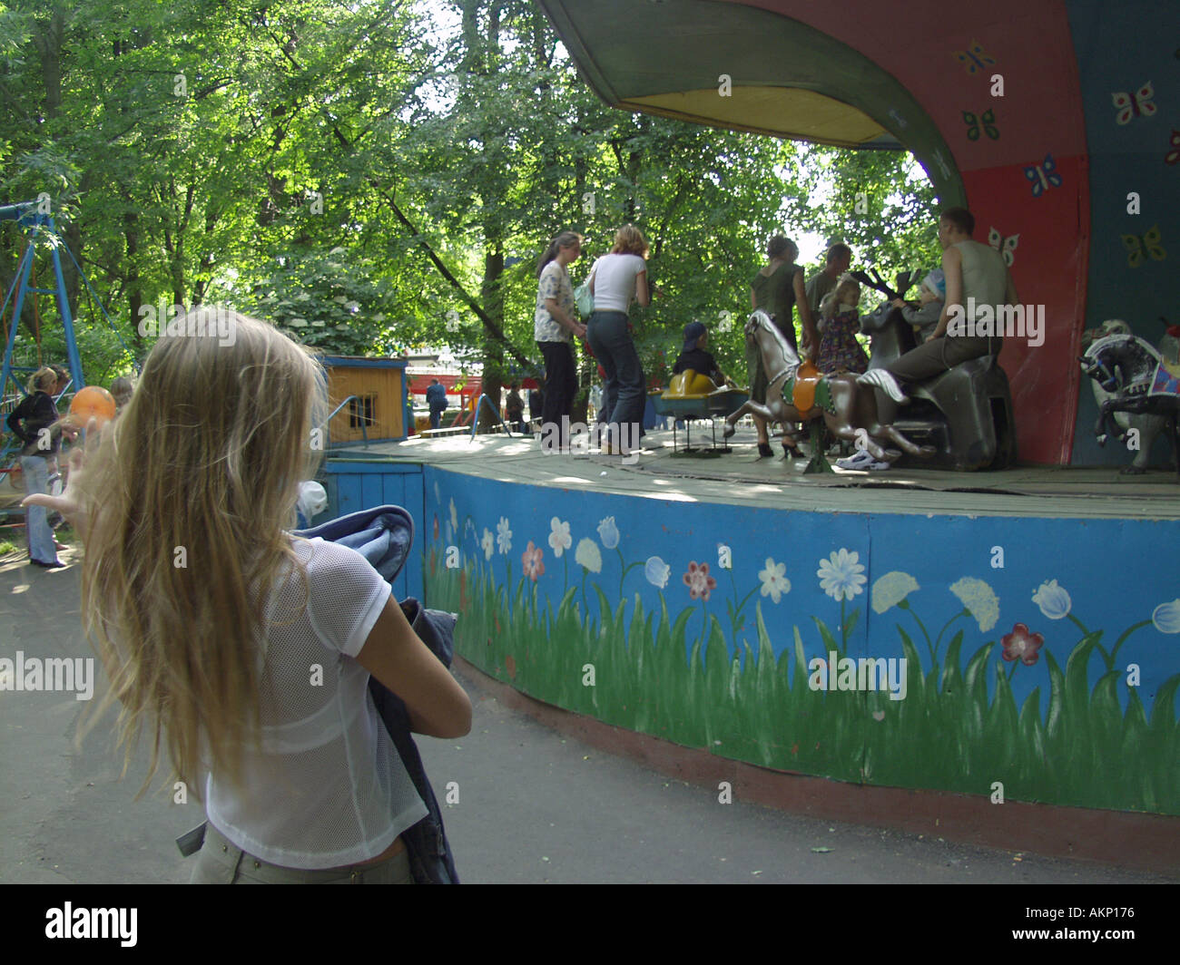 Young woman watching adults and children enjoying a fairground ride in Gomel Park Gomel Belarus Stock Photo