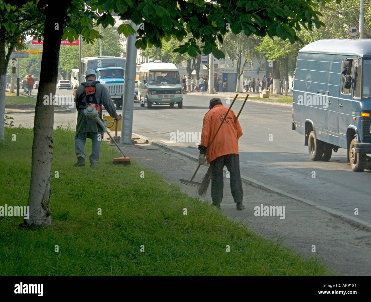 Street cleaners using powered strimmer and hand tools on Sovetskaya Street in Gomel Belarus Stock Photo