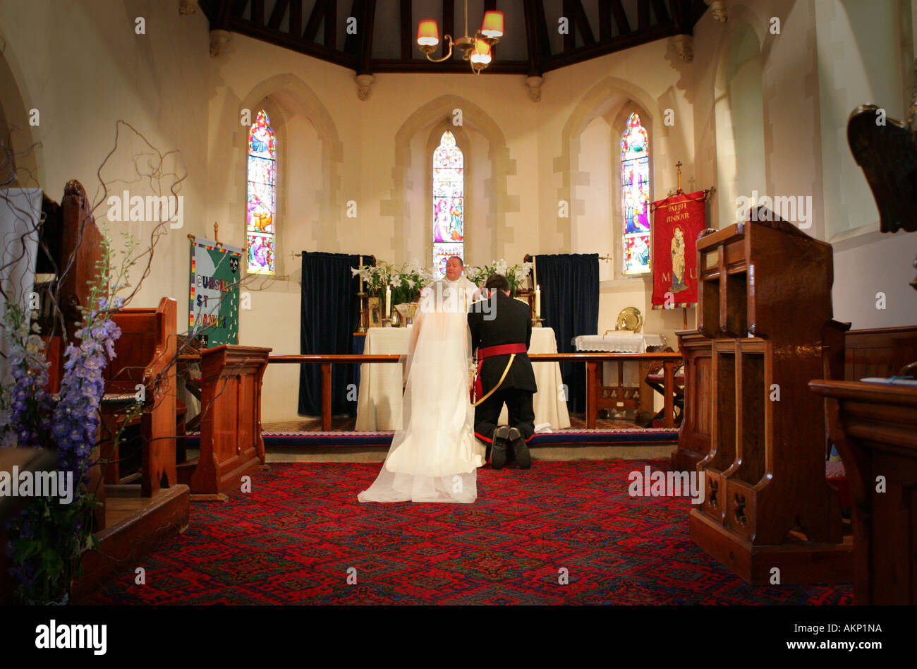 Bride and groom kneel at altar during typical catholic wedding ceremony