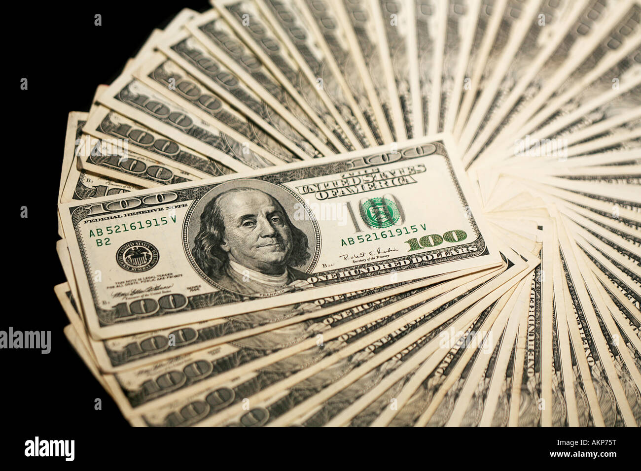 One hundred dollar bills in round wheel shape on black background Stock Photo