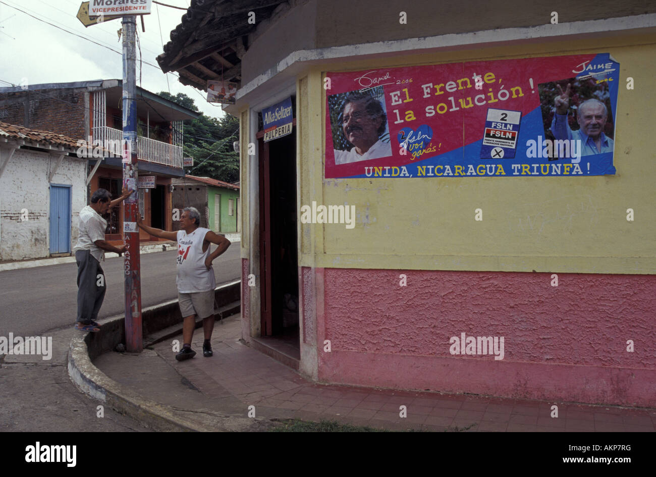 Two men chatting beside an FSLN 2006 presidential elections campaign poster in Moyogalpa, Isla de Ometepe or Ometepe Island, Nicaragua. Stock Photo