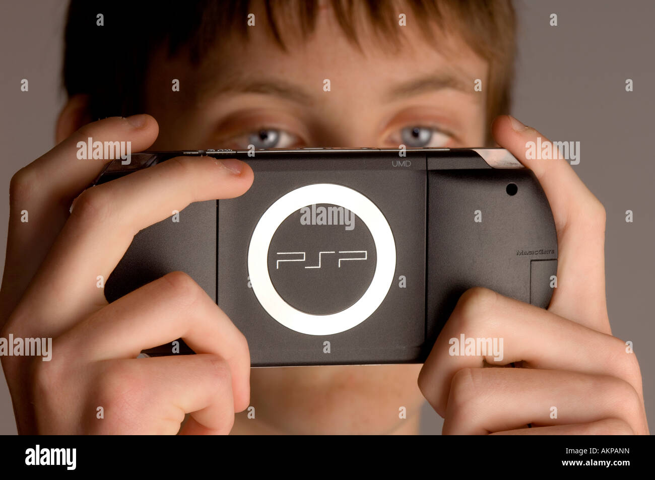 A young teenage boy playing on Sony PSP hand-held computer game console. Stock Photo