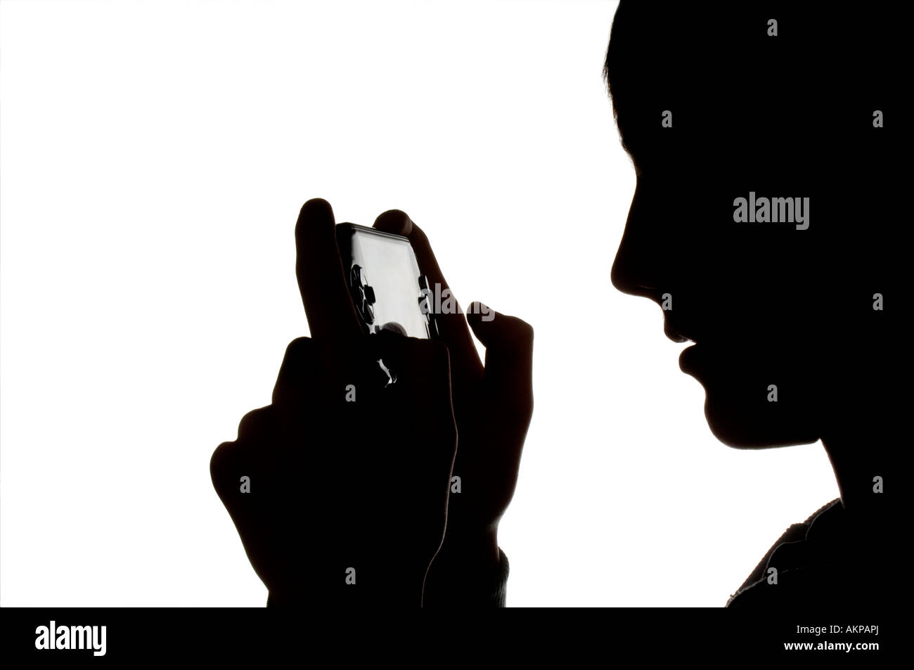 A silhouette of a young teenage boy playing on a Sony PSP hand-held computer game console. Picture by Jim Holden. Stock Photo