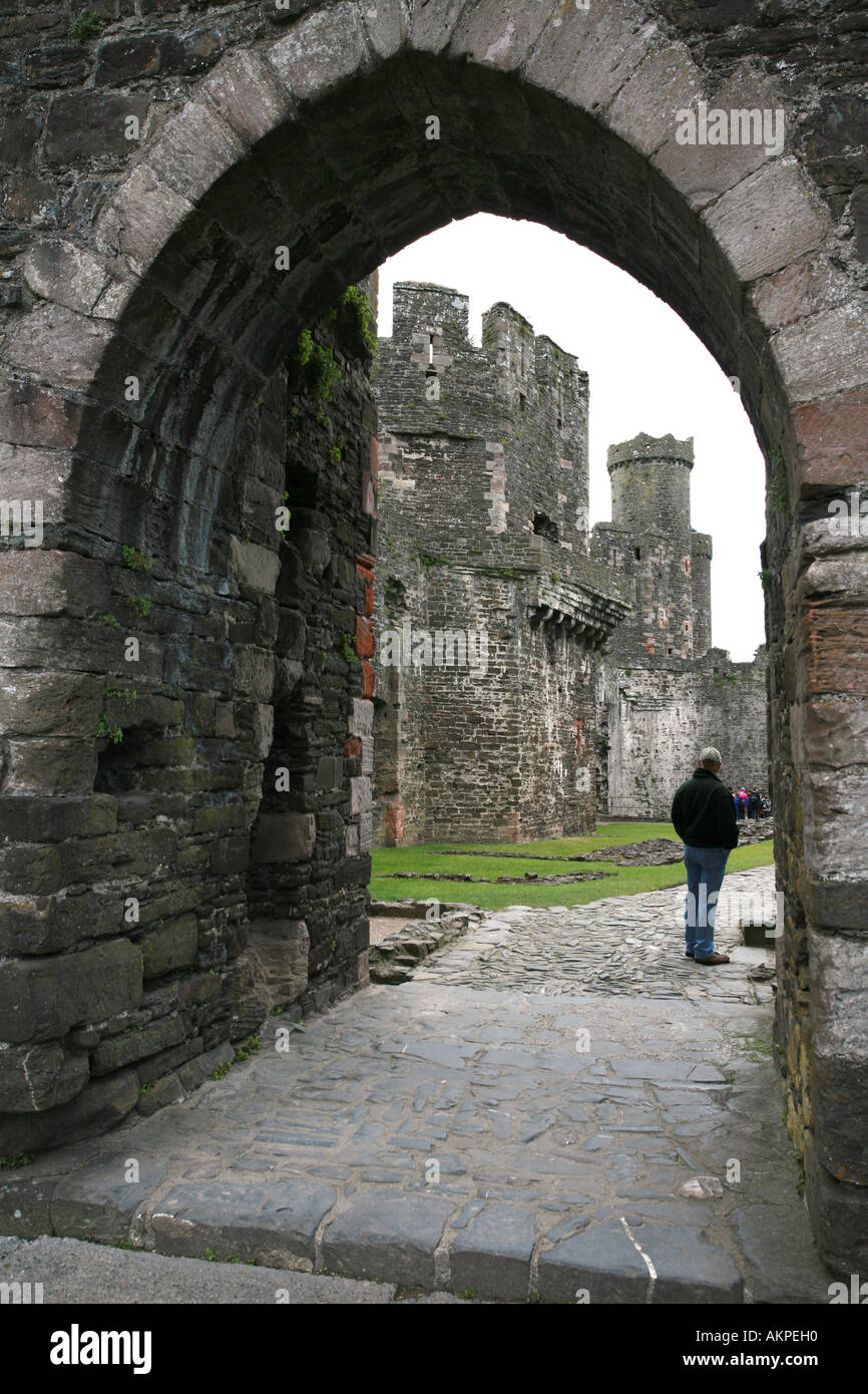 A tourist stands inside one entrance to world famous North Wales tourist attraction Conwy Castle in Sowdonia National Park UK GB Stock Photo