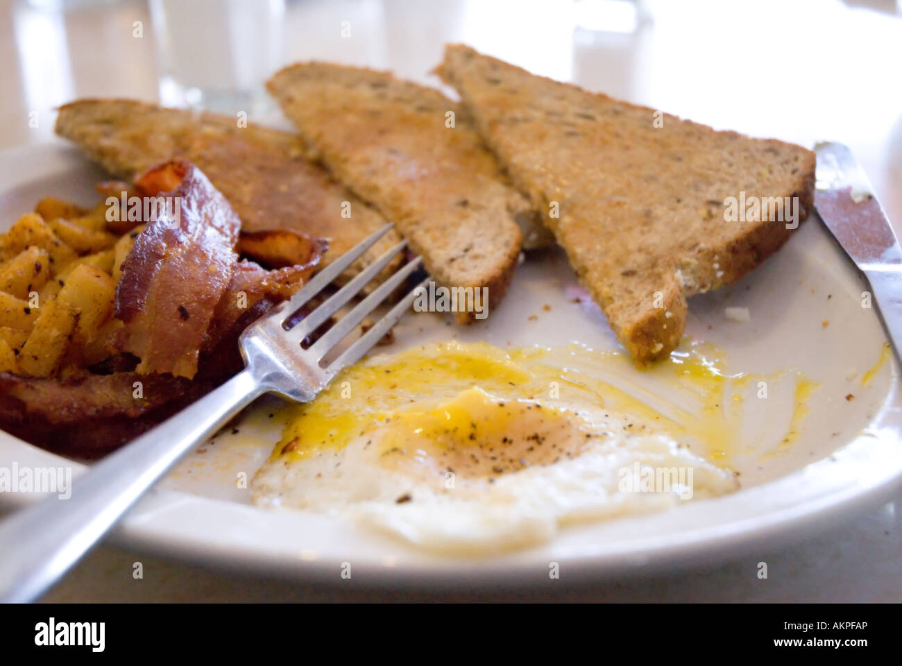 A plate of over easy eggs, bacon, toast and homefries at a diner in