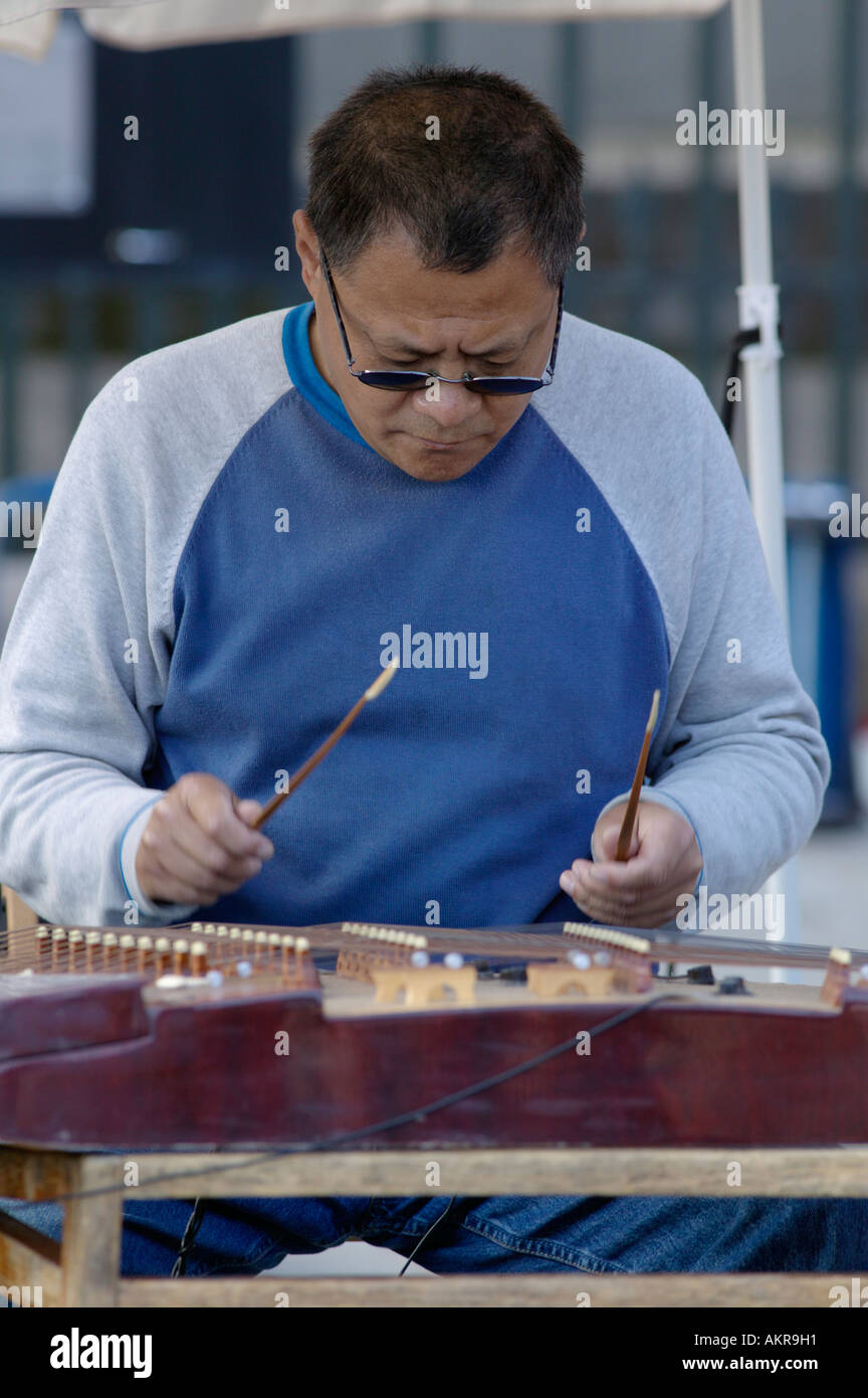 Chinese man playing a Yang Qin or Chinese dulcimer at the Edinburgh