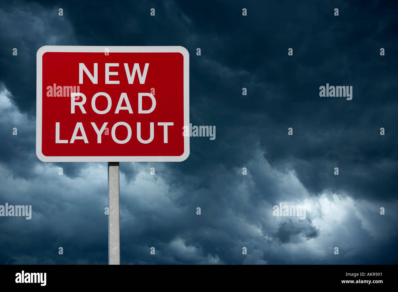 RED NEW ROAD LAYOUT WARNING SIGN WITH BLUE STORMY SKY AND CLOUDS IN BACKGROUND Stock Photo