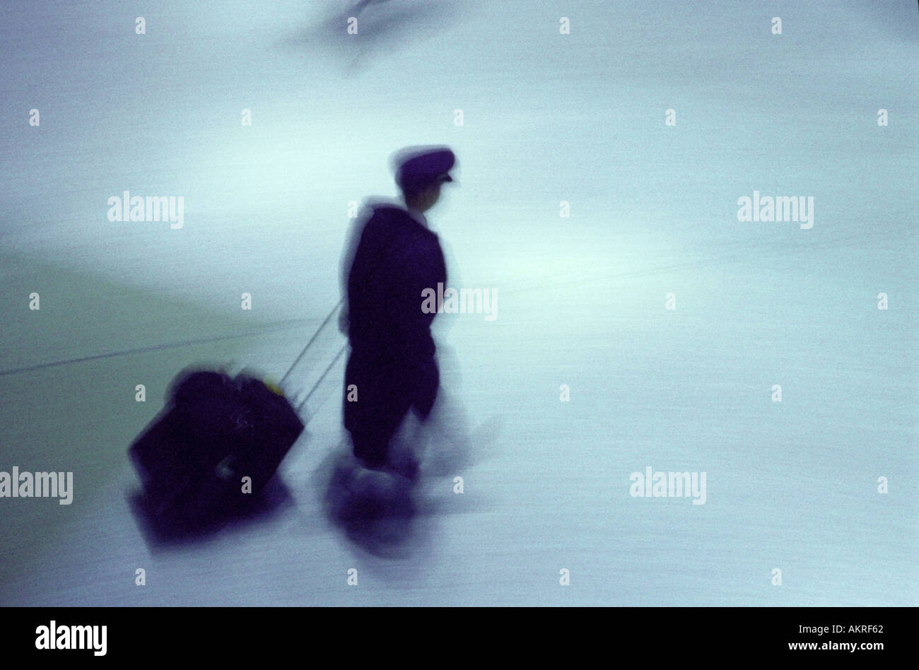 airline pilot walking in airport in motion Stock Photo