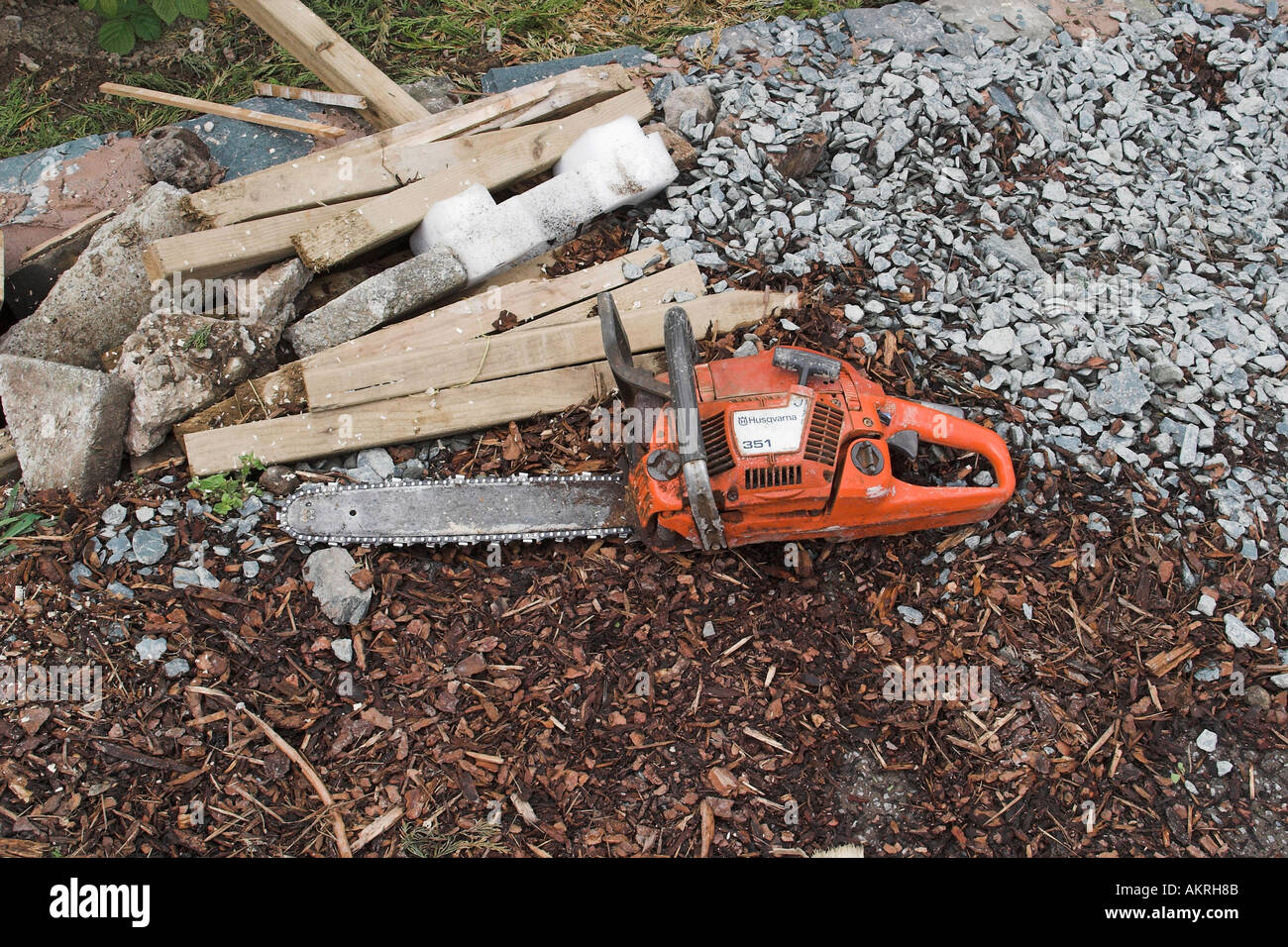 chainsaw on the ground next to a pile of wood in a garden which is ...