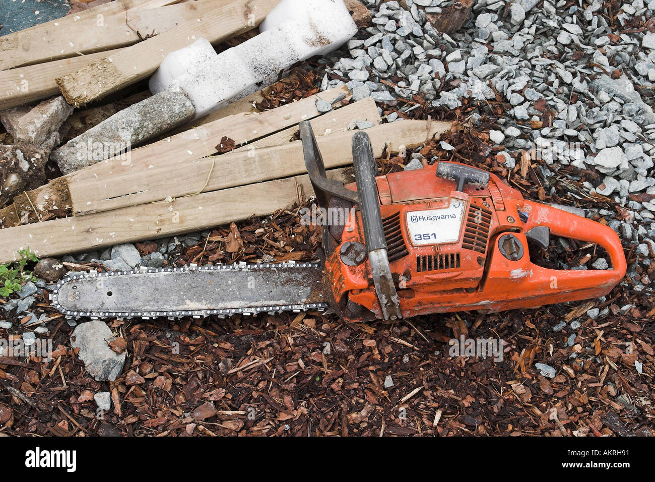 chainsaw on the ground next to a pile of wood in a garden which is ...