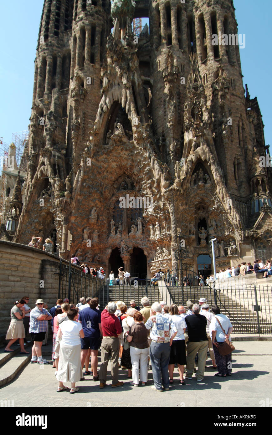 Group of tourists people outside long running construction building site of Roman Catholic church the Basílica de la Sagrada Família   Barcelona Spain Stock Photo