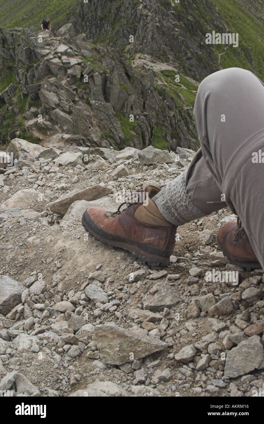 female walker resting on slope on striding edge showing footwear used ...