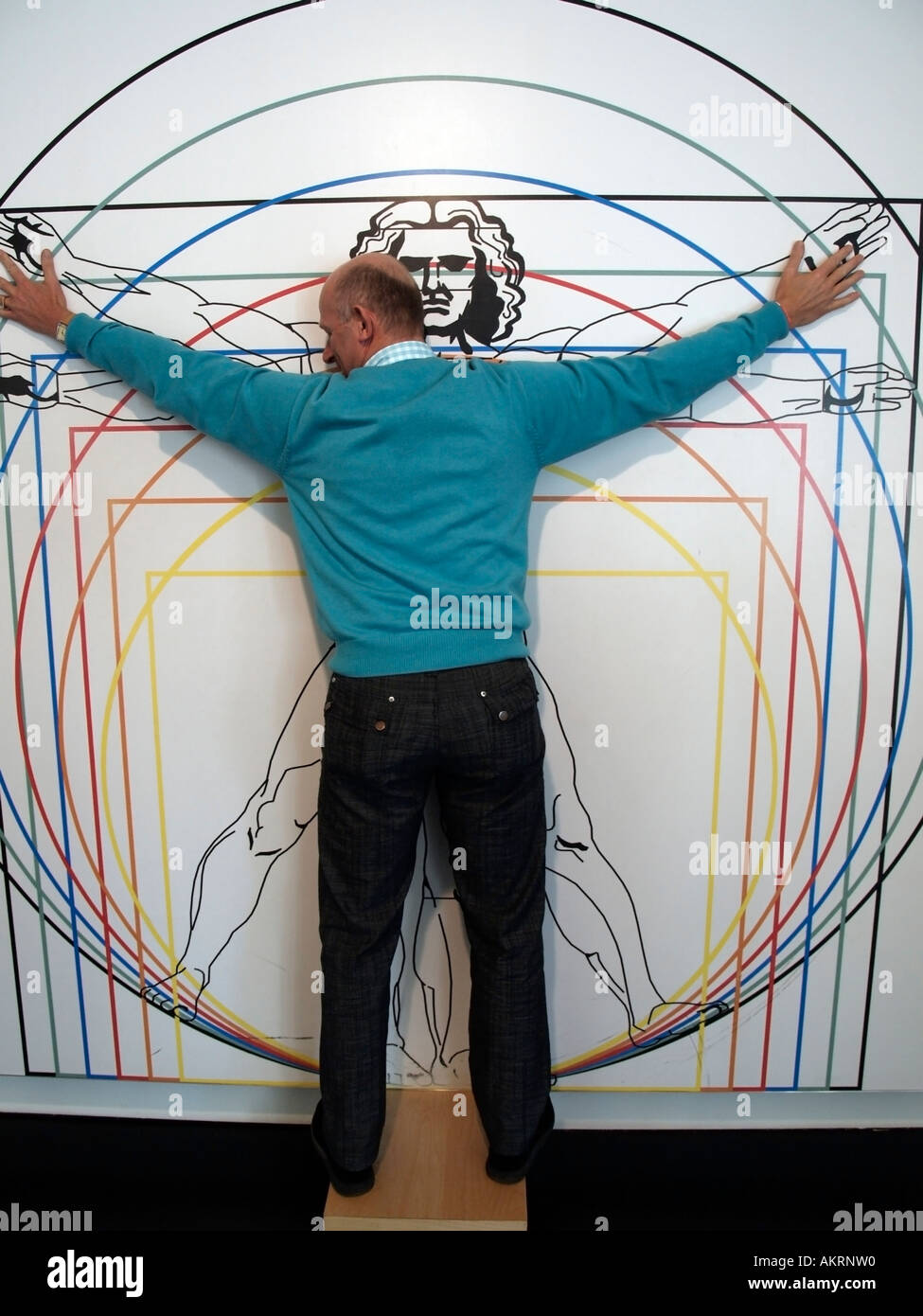 man standing with streched arms at wall with an anatomical drawing according to Leonardo da Vinci in the museum Mathematikum Stock Photo