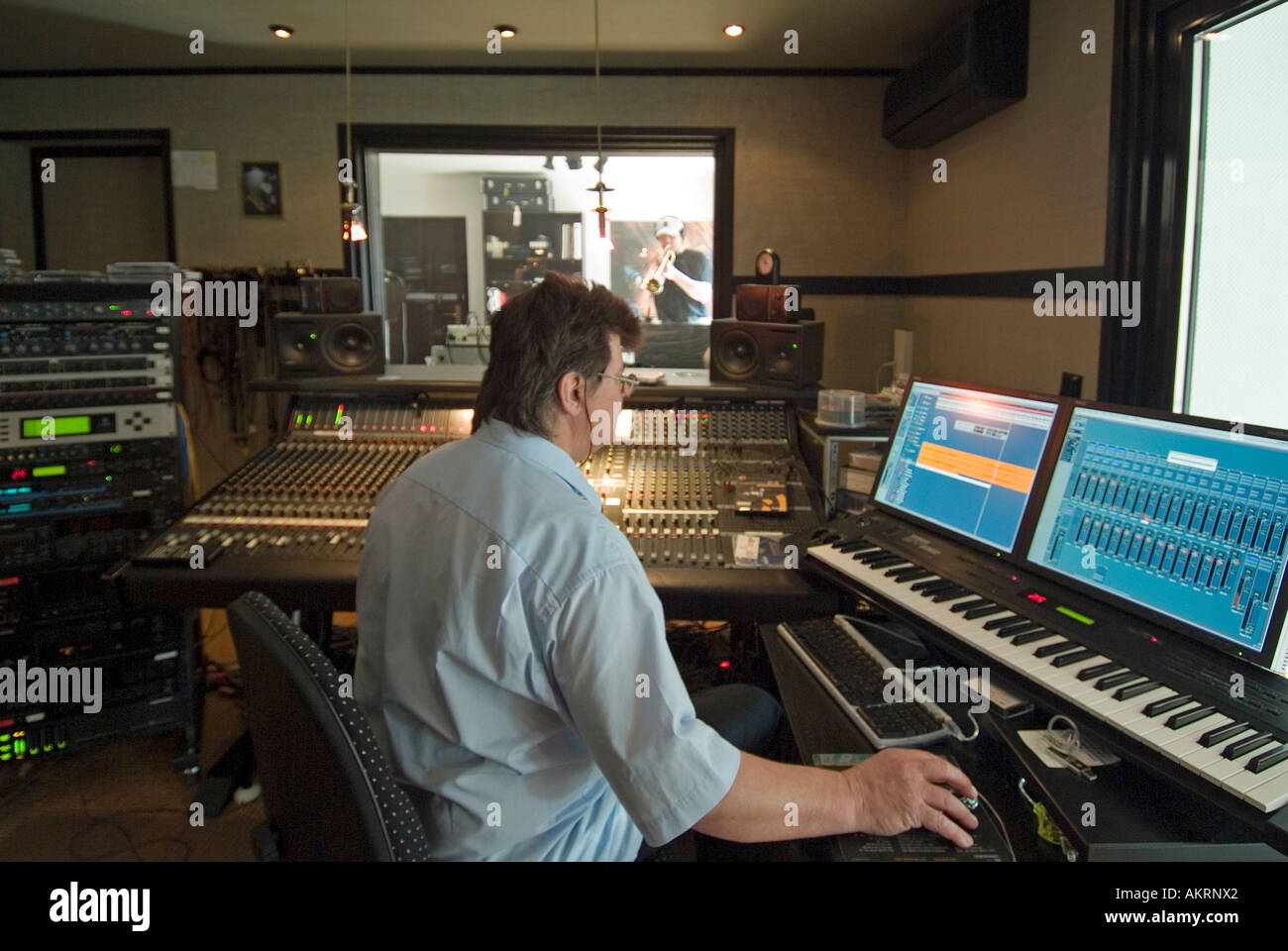working in recording studio musician audio engineer two men with musical instruments keybords and trumpet trump in a studio Stock Photo