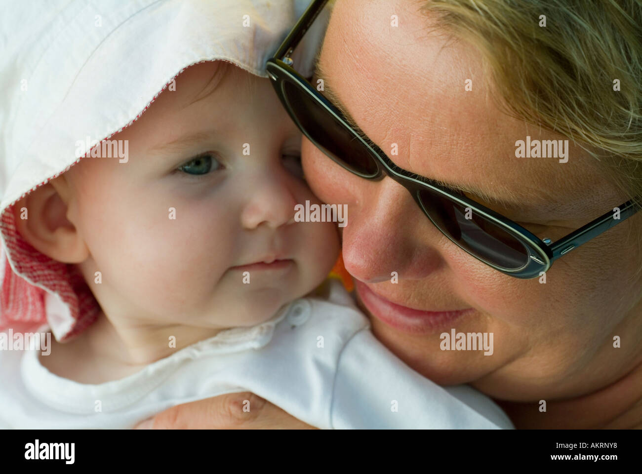 grandmother and grandchild baby of 8 months with sun hat and a woman in age of about 45 to 55 years with sunglasses Stock Photo