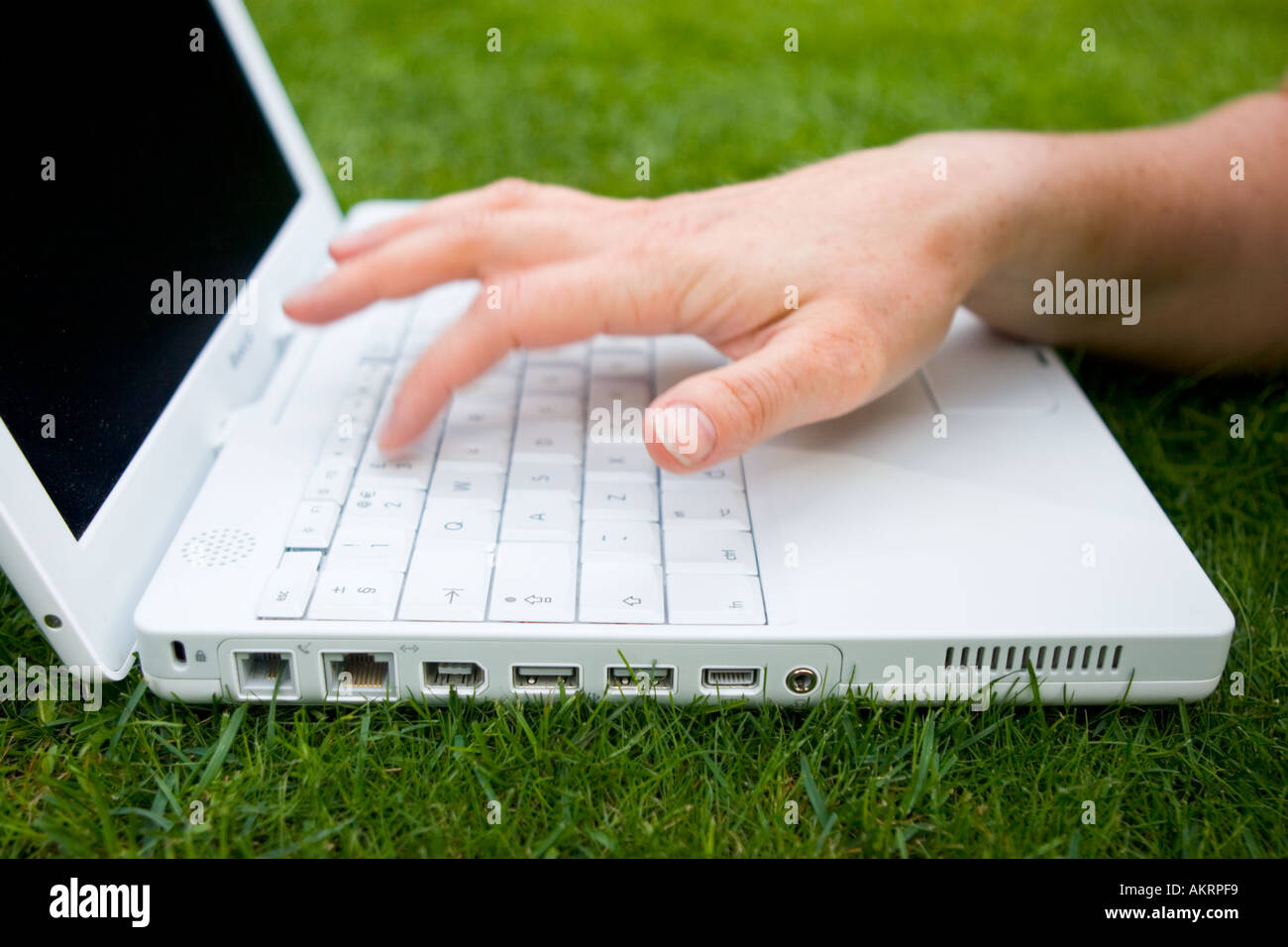 Female hands using a white laptop outdoors on a lawn Stock Photo