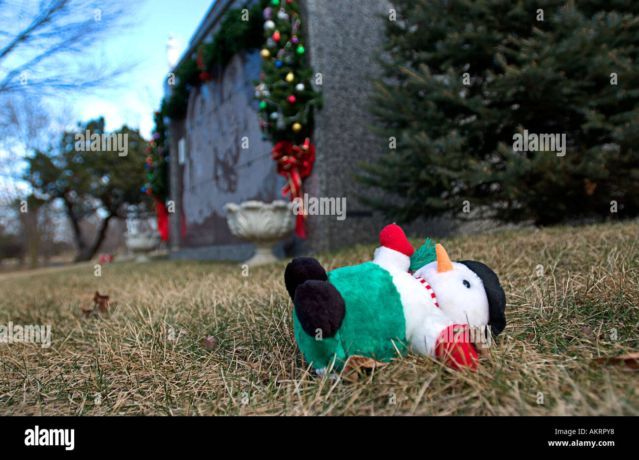 Stuffed Frosty the Snowman laying in front of mausoleum at a cemetery Stock Photo