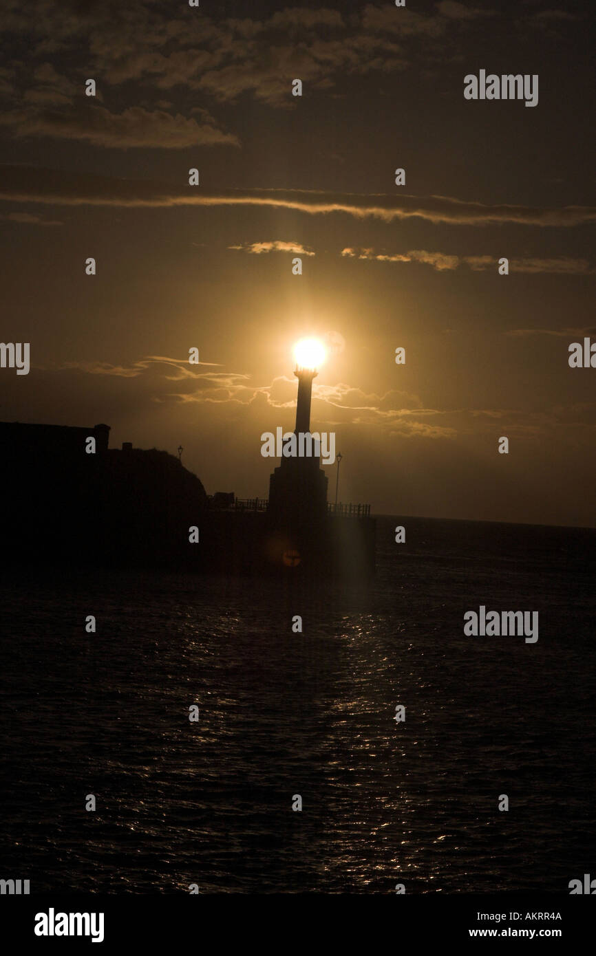 the sun over the top of a lighthouse in maryport, cumbria, uk looking like the lighthouse light is on Stock Photo