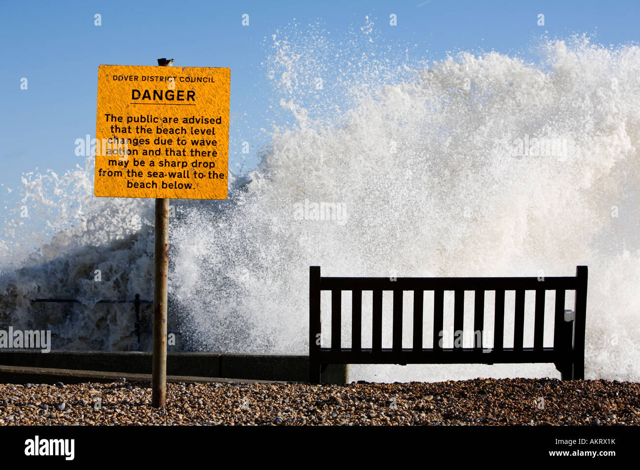 Kingsdown Signs Danger sign on seafront with huge wave hitting seawall, Kingsdown, Kent ...