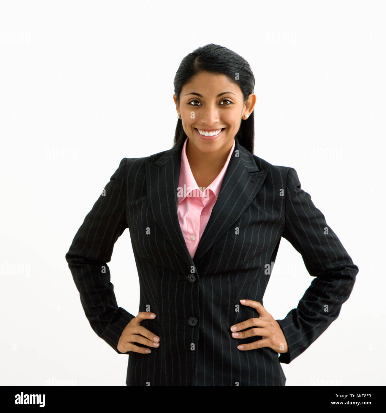 Portrait of smiling businesswoman with hands on hips against white ...