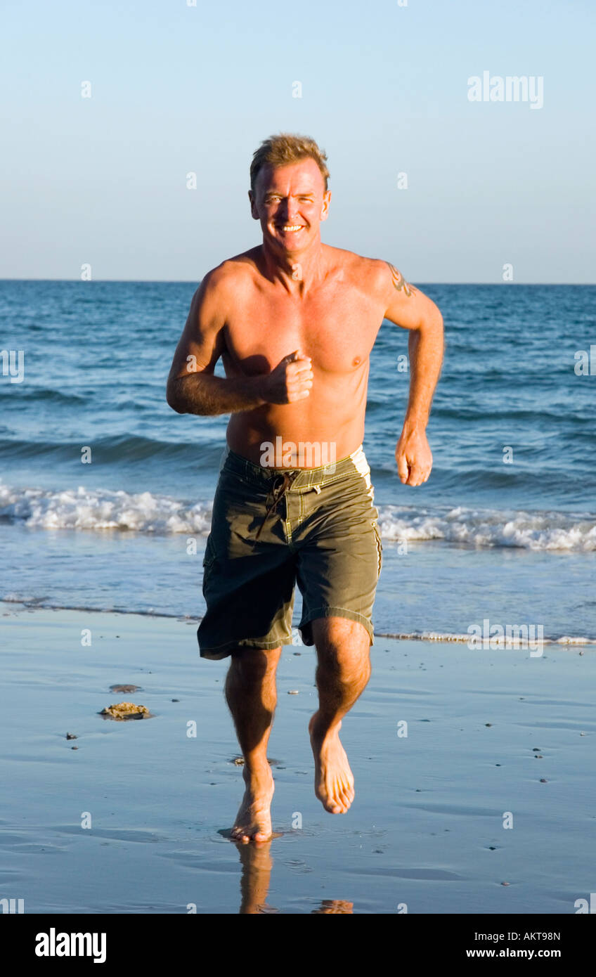 Colour portrait of a  handsome 43 year old man jogging along the beach. Stock Photo