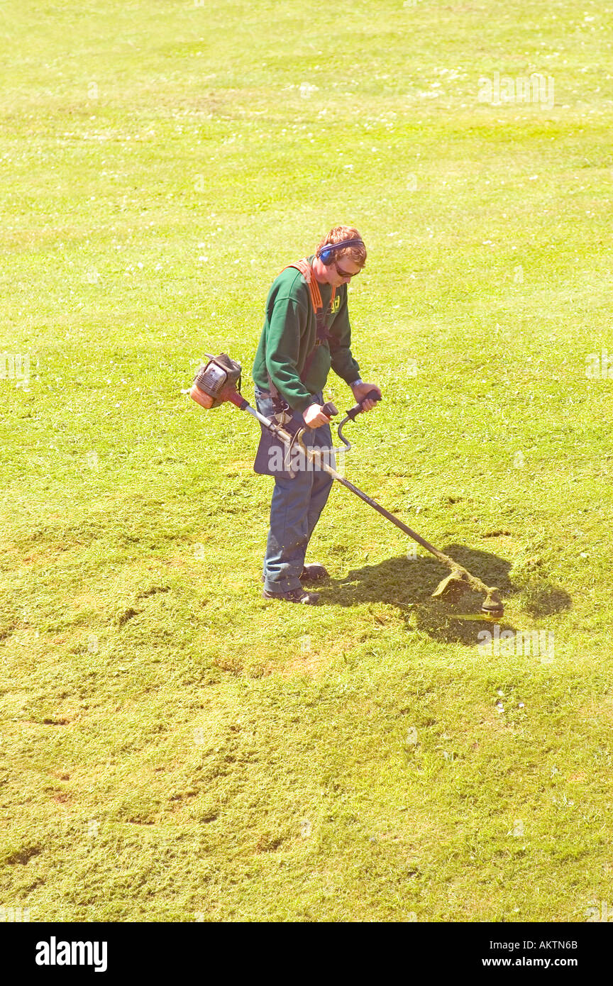 Council worker strimming grass at Caephilly Castle, Caerphilly, Wales, UK. Stock Photo