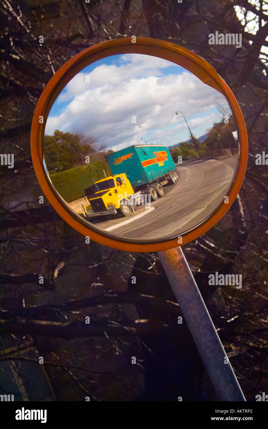 A loaded truck reflected in a convex mirror used to see around a blind corner Stock Photo