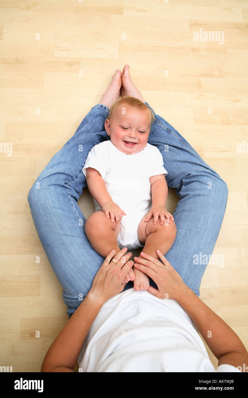 Baby Laying on Moms Legs Smiling Stock Photo