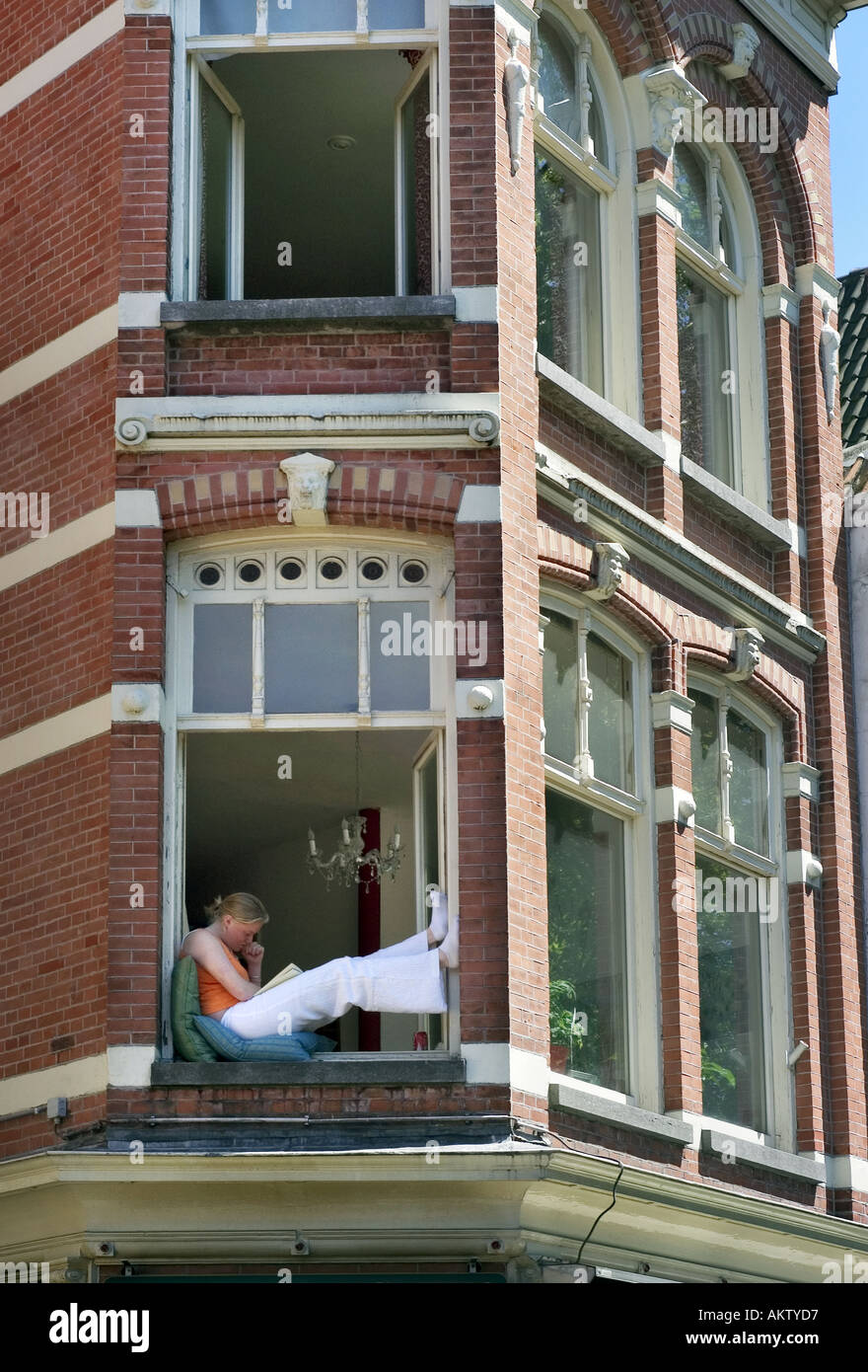 young woman sitting on the edge of a window Stock Photo