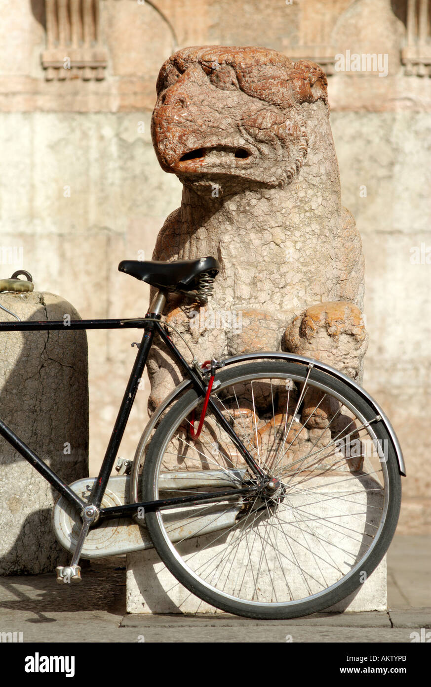Ferrara Italy A bicycle leaning against a centuries old marble sculpture of the Duomo Stock Photo