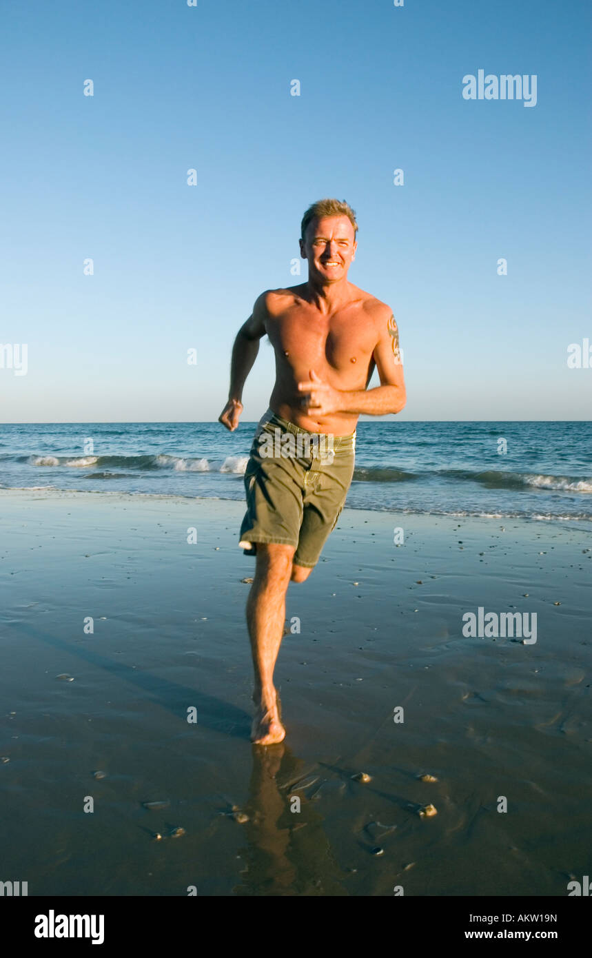 Colour portrait of 43 year old man jogging along a beautiful beach. Stock Photo