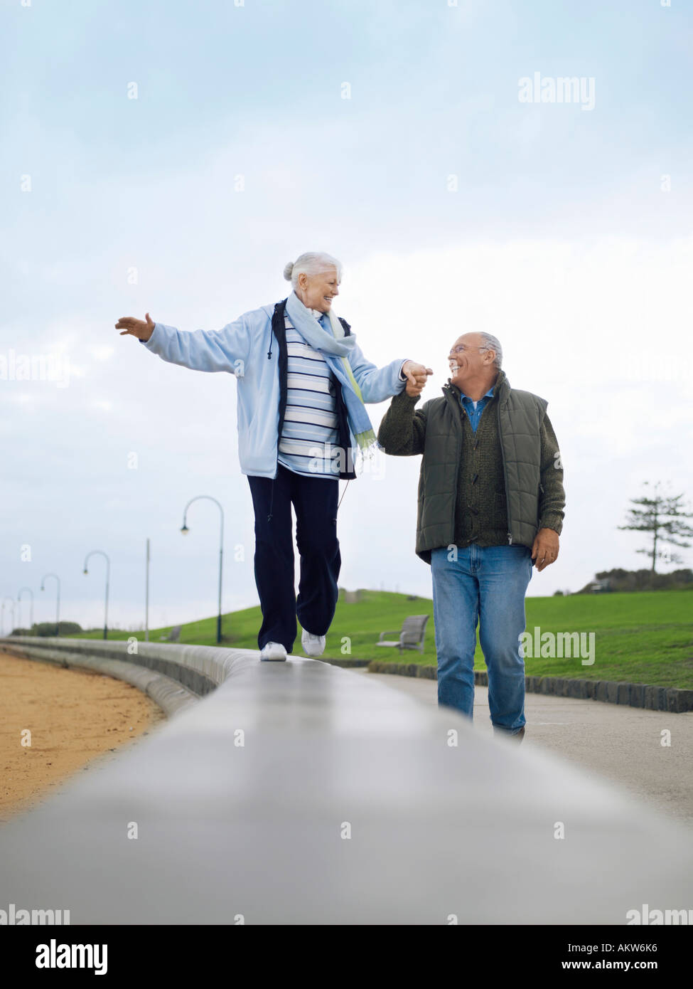 Senior couple walking on wall, holding hands Stock Photo