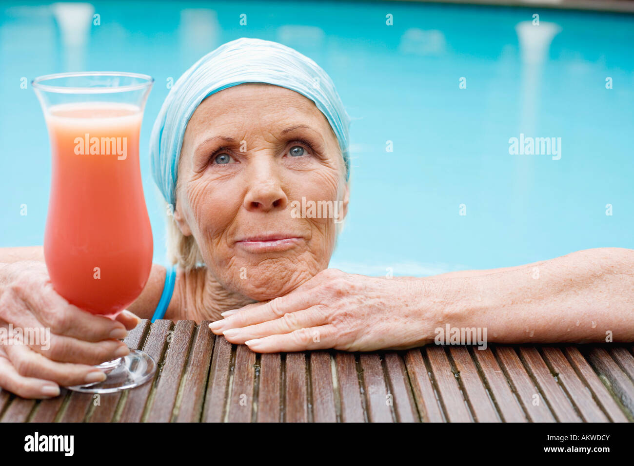 Germany, senior woman having cocktail at pool Stock Photo