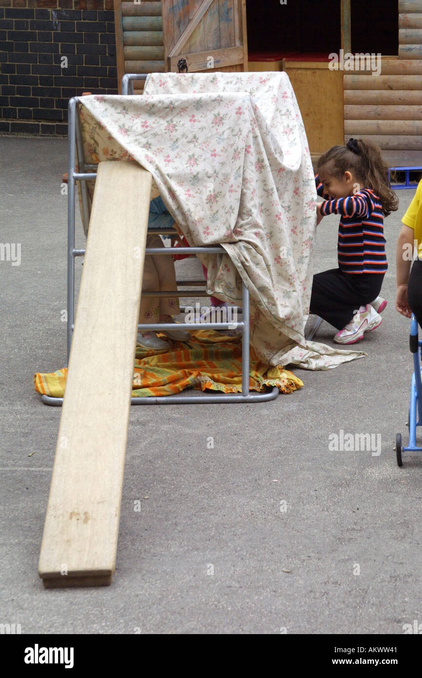 nursery children making tents out of blankets in playground Stock Photo
