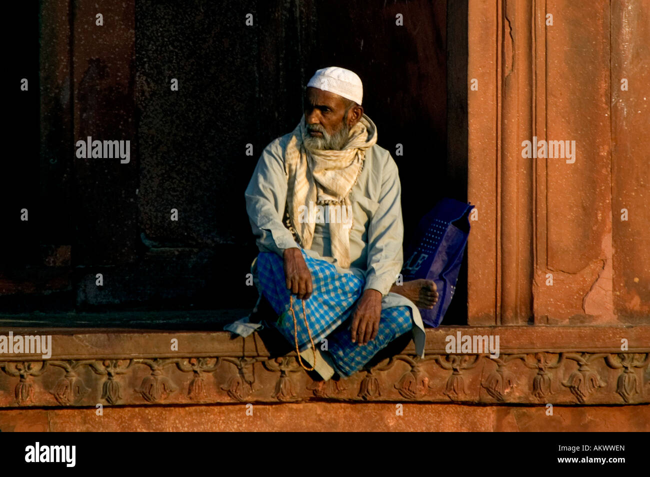 A Muslim man sits within the walls of the historic Red Fort (Lal Qila) in Old Delhi, India. - Stock Image